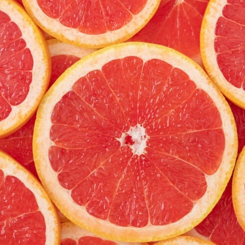 Close-up of a sliced pink grapefruit, a source of essential oils, revealing its juicy segments and vibrant pink hues