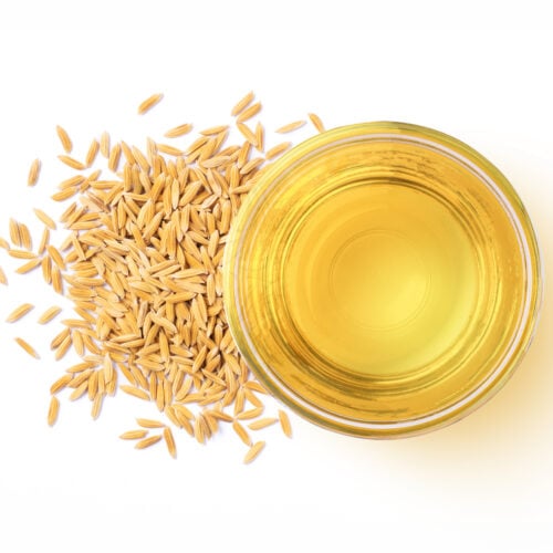 Rice bran oil extract with paddy unmilled rice isolated on white background. Top view. Flat lay.