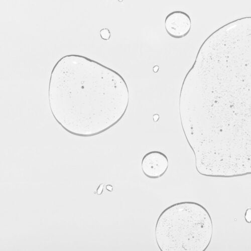 Cosmetic product clear drops and space for design on white surface close upper view. Skincare and dermatological procedures